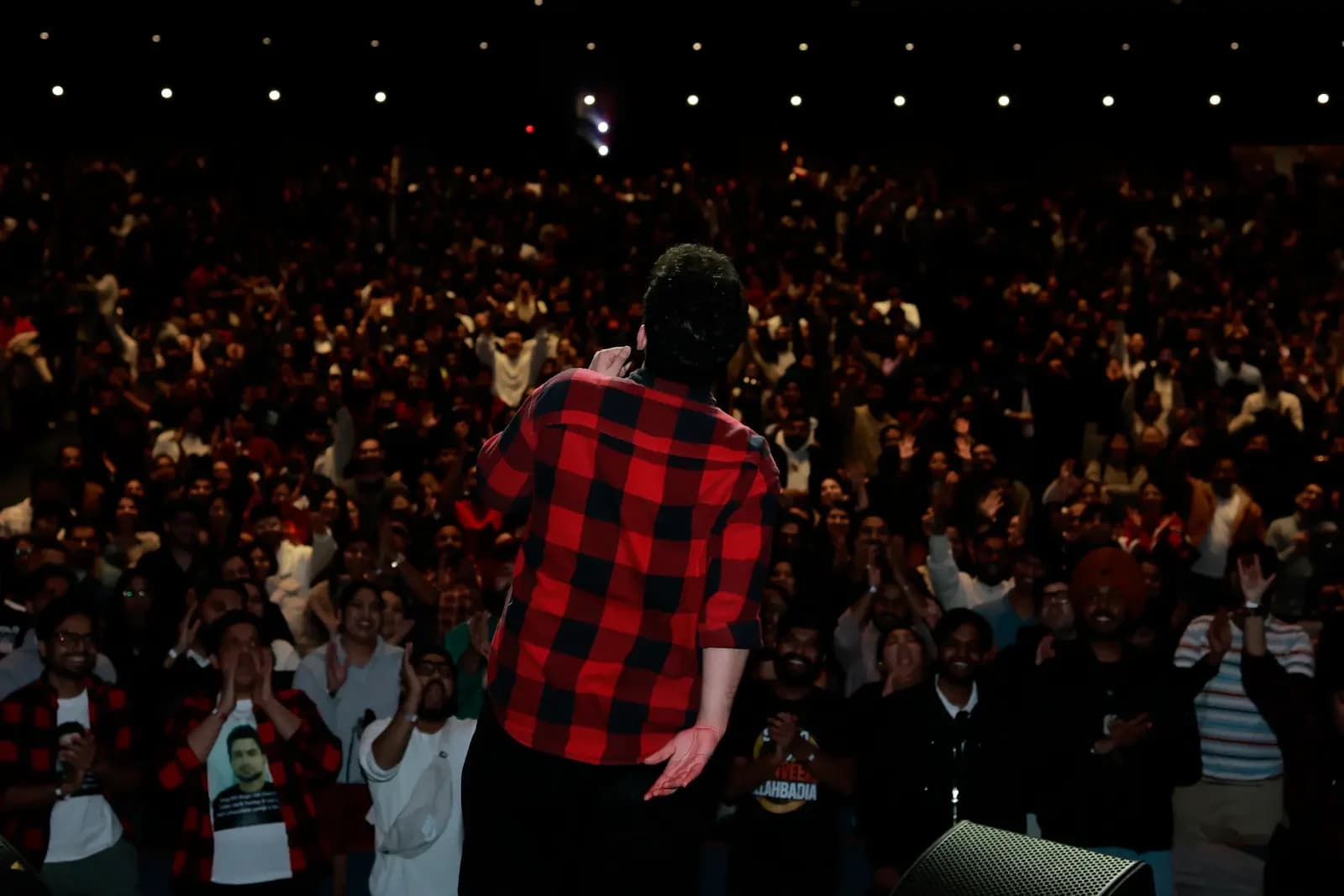 Samay Raina raising his arms to the crowd at Meridian Hall in Toronto